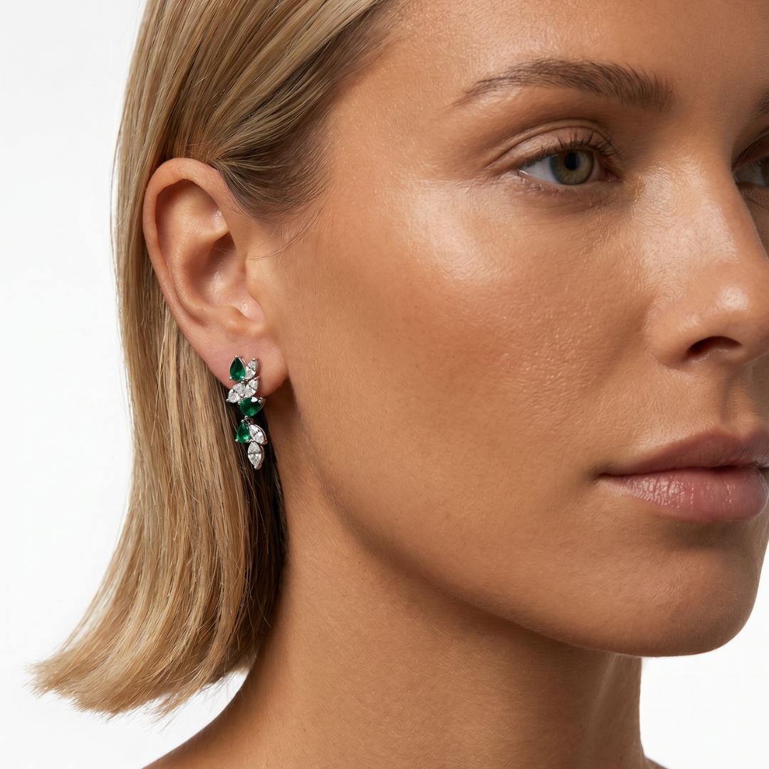 Modelo llevando pendientes largos de plata de ley 925 con baño en rodio y circonitas blancas y verde esmeralda de NILU.