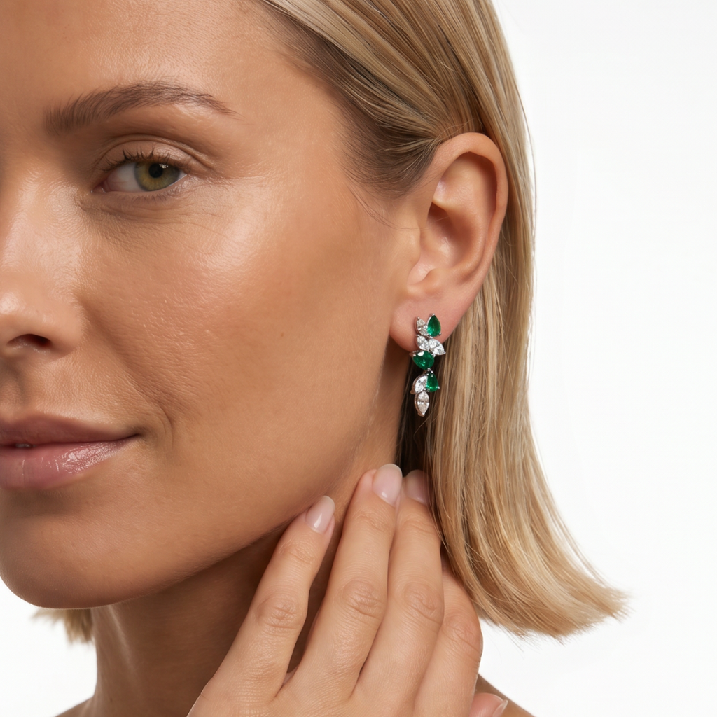 Modelo llevando pendientes largos de plata de ley 925 con baño en rodio y circonitas blancas y verde esmeralda de NILU.